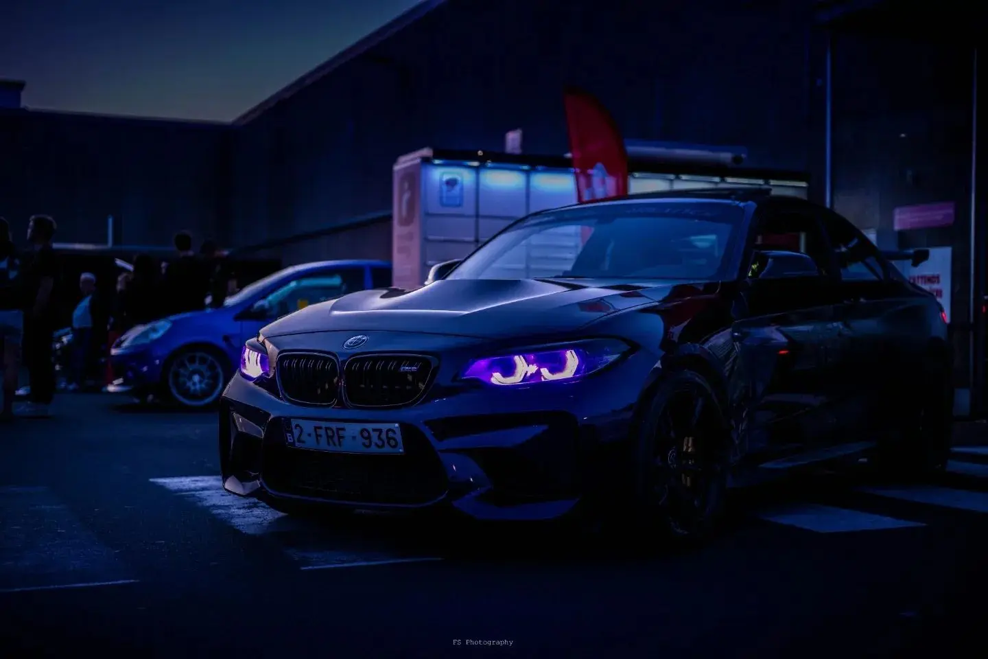 BMW sombre aux phares violets photographiée de nuit