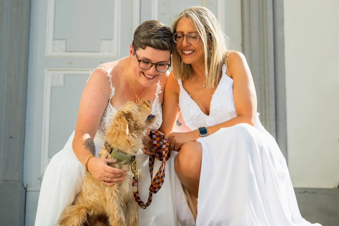 Coralie et Meya sourient avec leur chien le jour de leur mariage